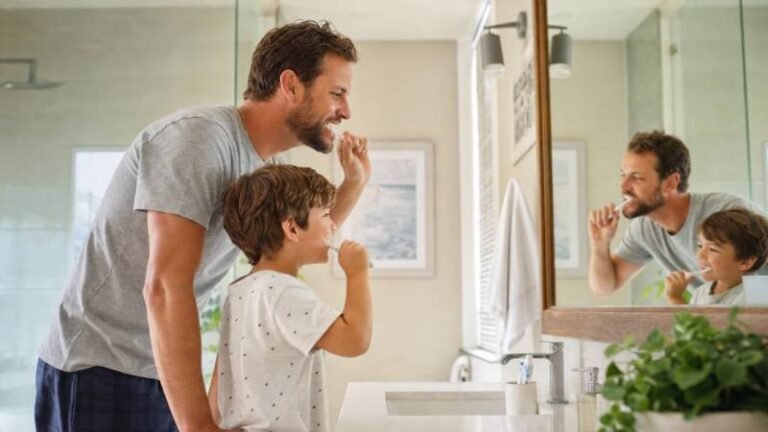 Father and son brushing teeth together in bathroom